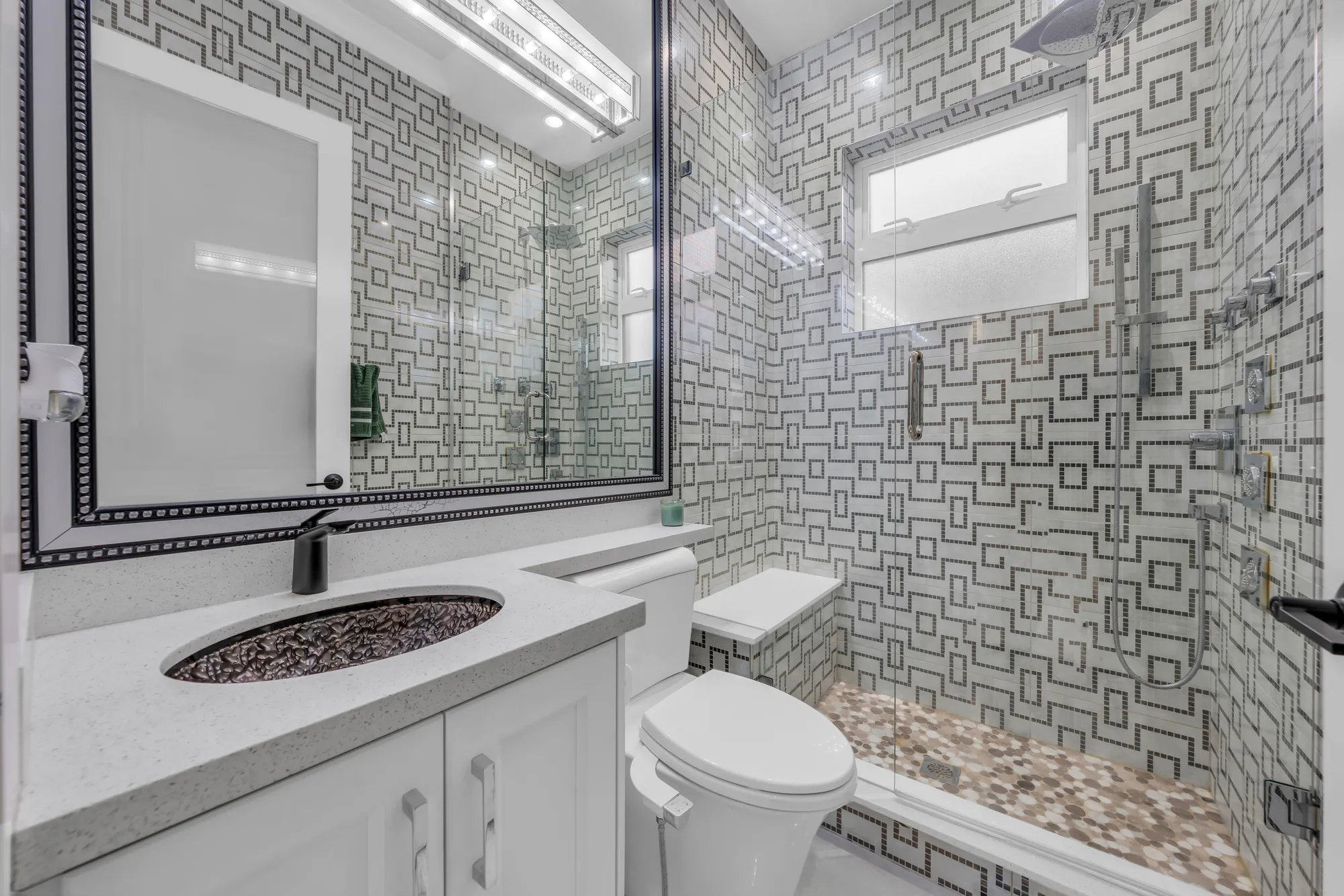 The upper bathroom: a tub with a subway-tile surround under a window, a white vanity with a copper basin, a mirror in a black frame