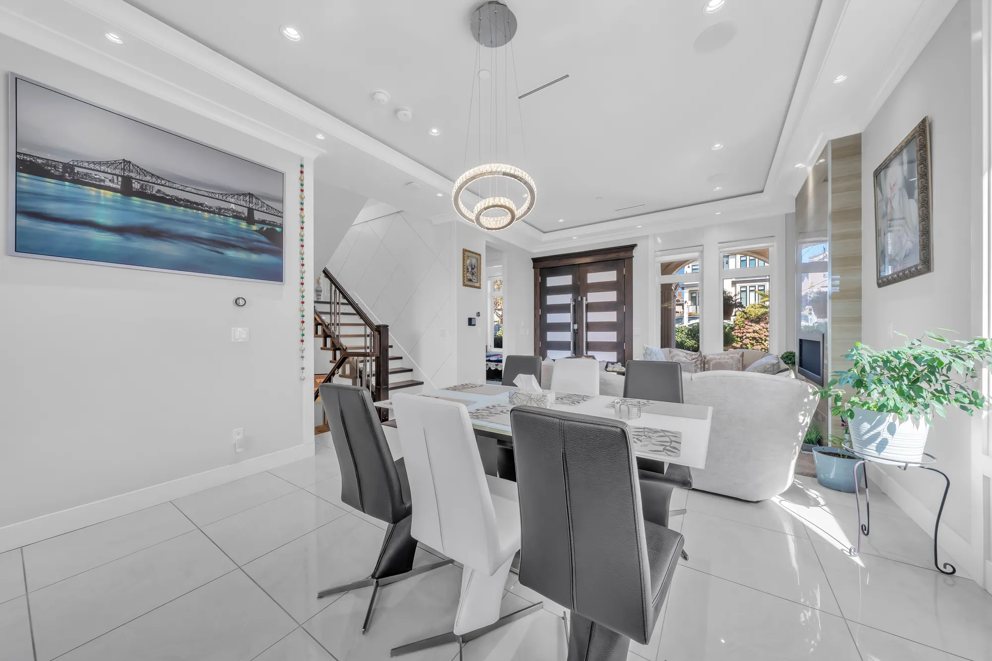 The dining table and chairs, a print of a bridge on the wall, the stair and the front doors beyond