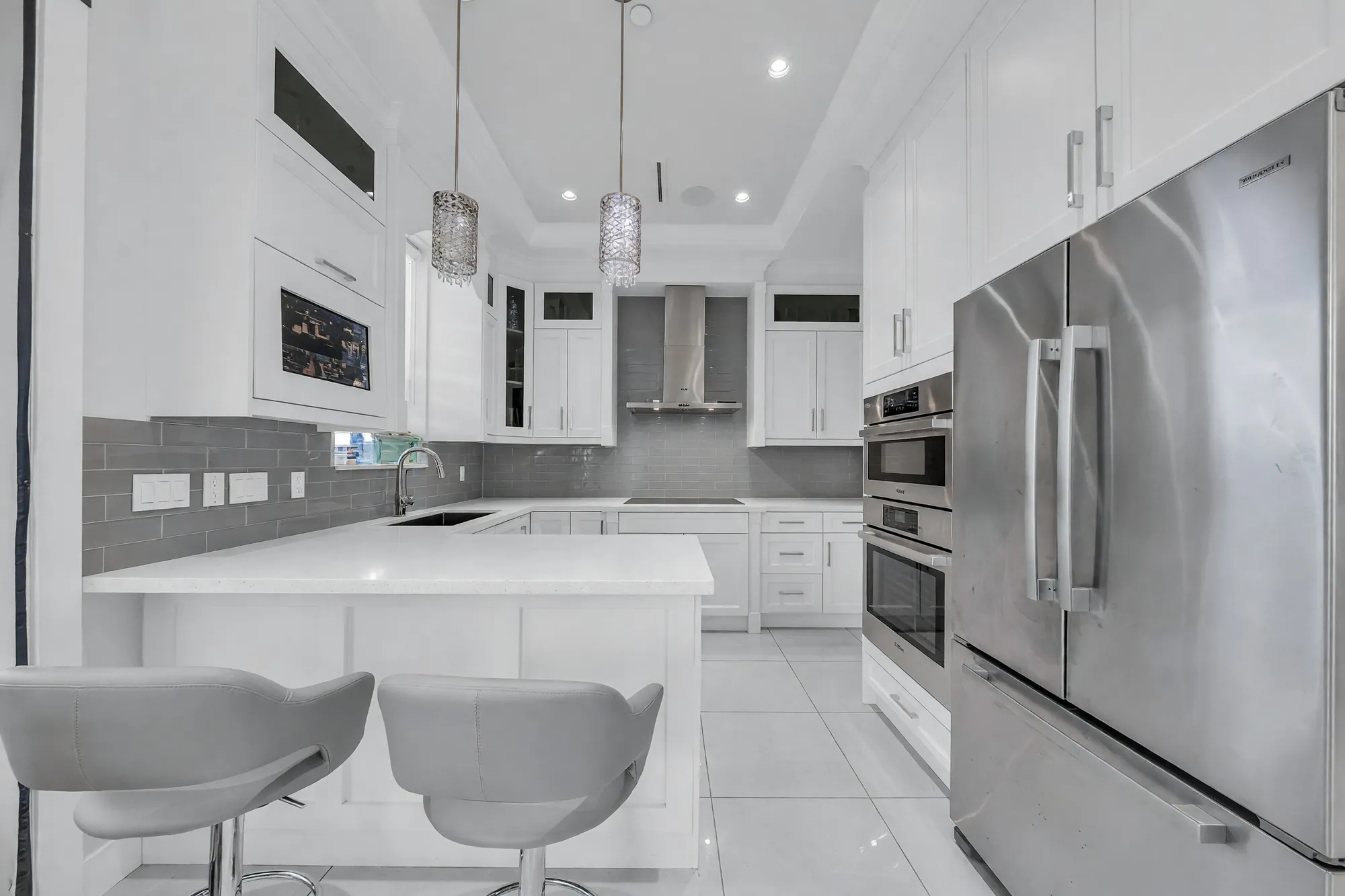 The kitchen from the island's end: the refrigerator, the ovens, the range hood and the window