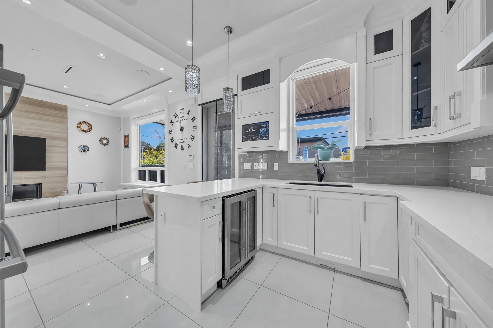 The kitchen toward the family room: the island, the wine fridge, the family room's white sectional and fireplace beyond
