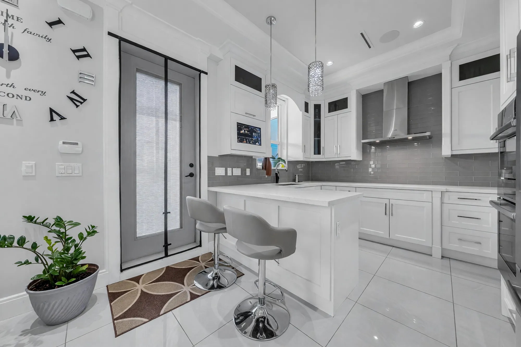 The kitchen from the balcony door: the island and stools, the range hood, a plant by the door