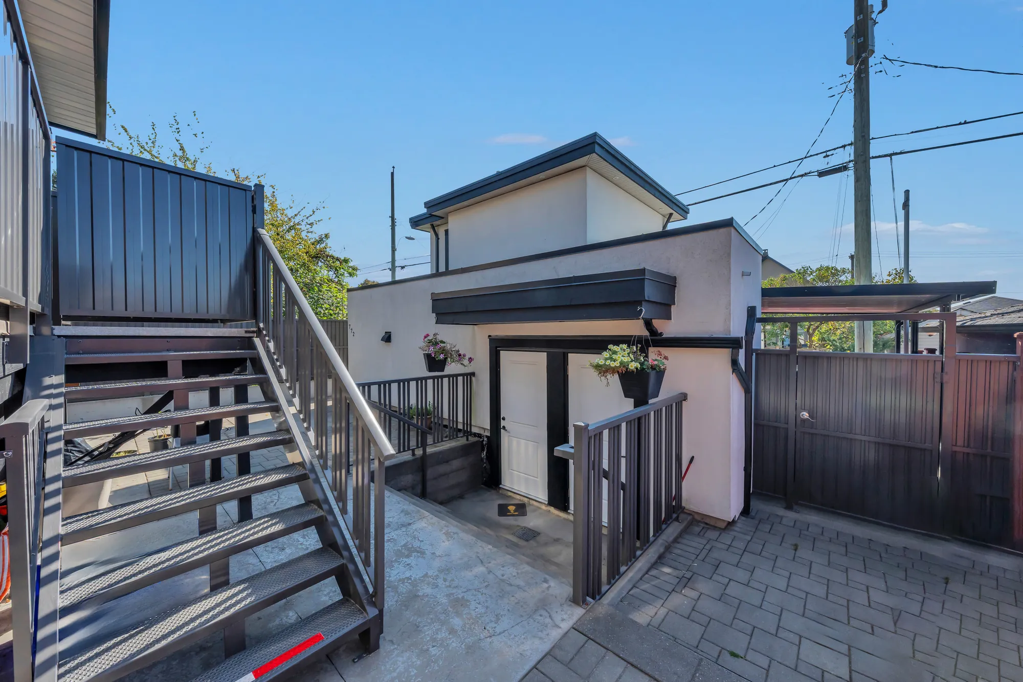 The courtyard from under the balcony stairs: the laneway house's door, the carport's roof, the gate to the lane