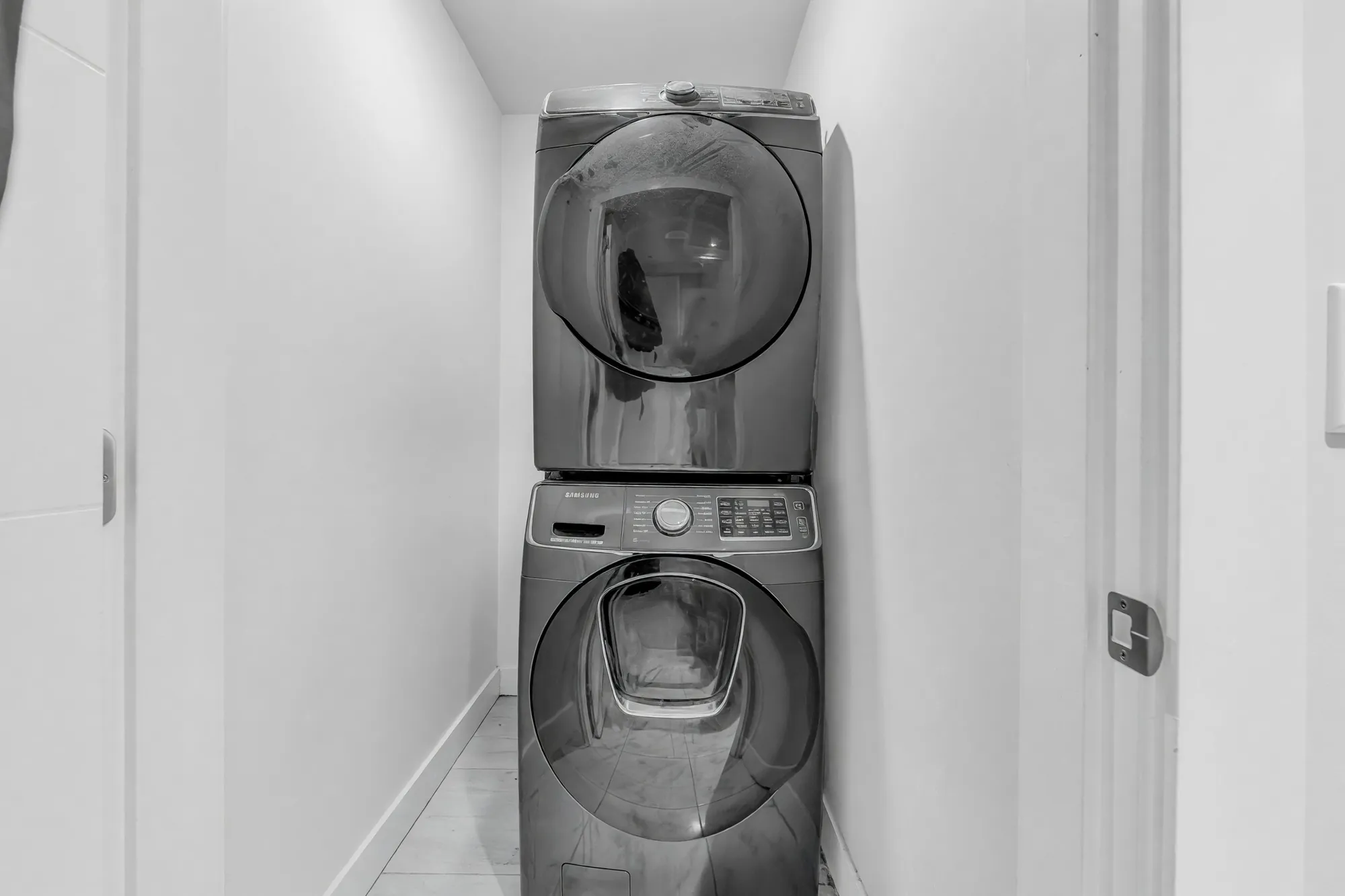 A laundry closet with a stacked washer and dryer, white walls