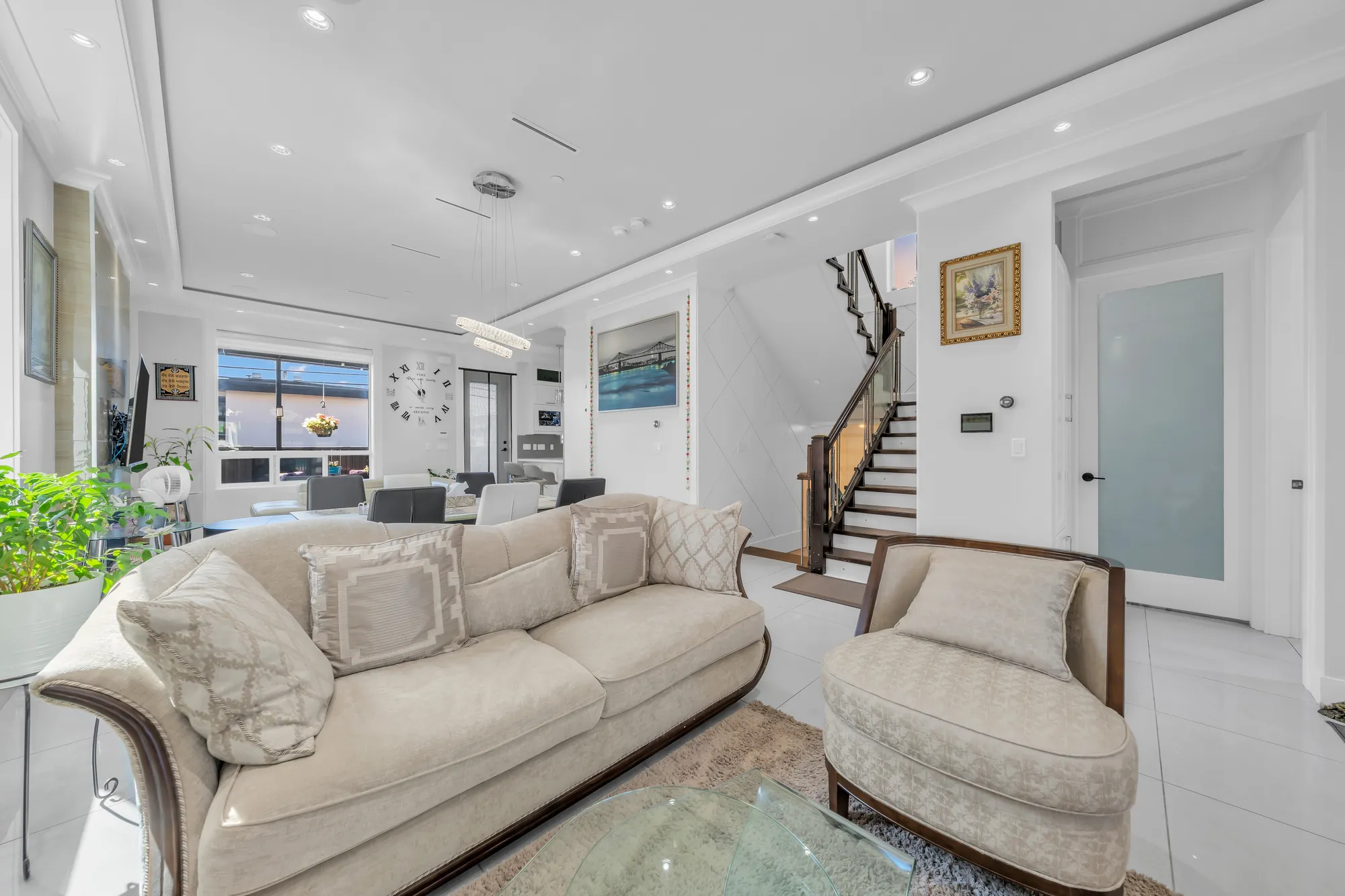 The living room's sofas along the side windows, the stair with its dark rail beyond