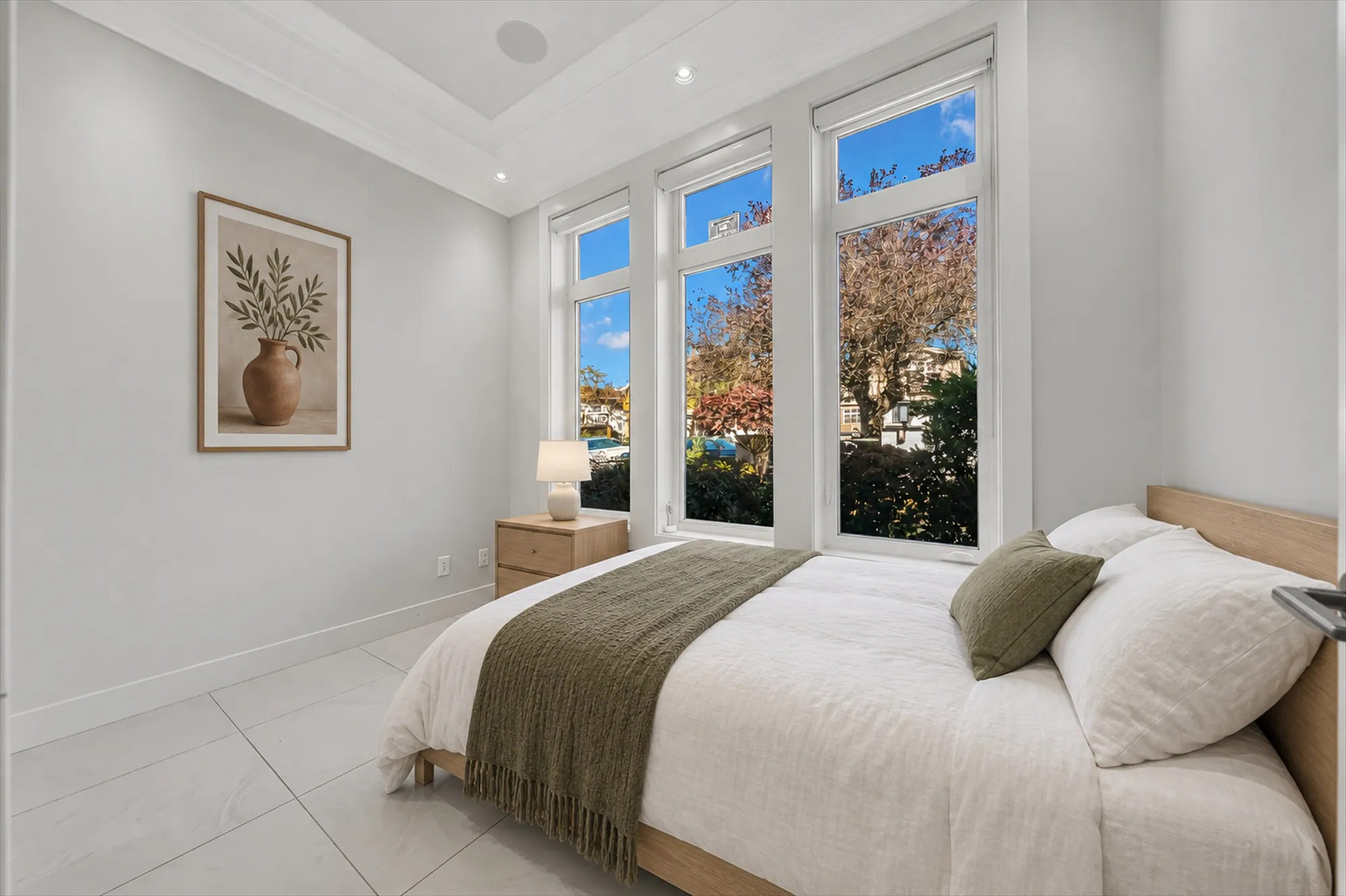 The same room virtually staged as a bedroom: a bed with a green throw, a night table, a lamp and a picture added