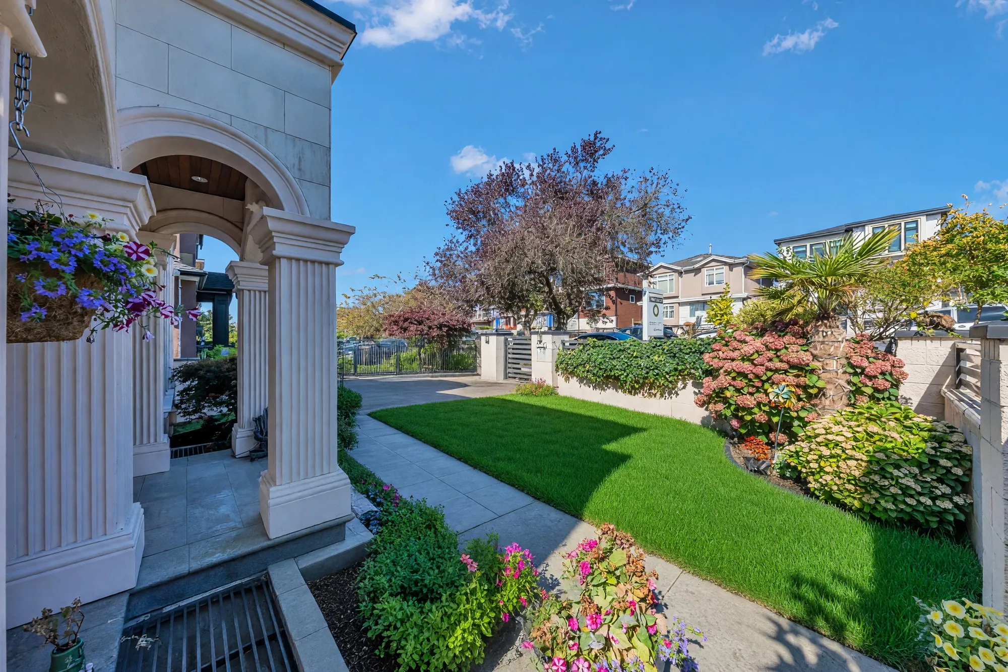 From the porch, past a column and a hanging basket, down the walk to the gate and the street, the lawn and hydrangeas either side