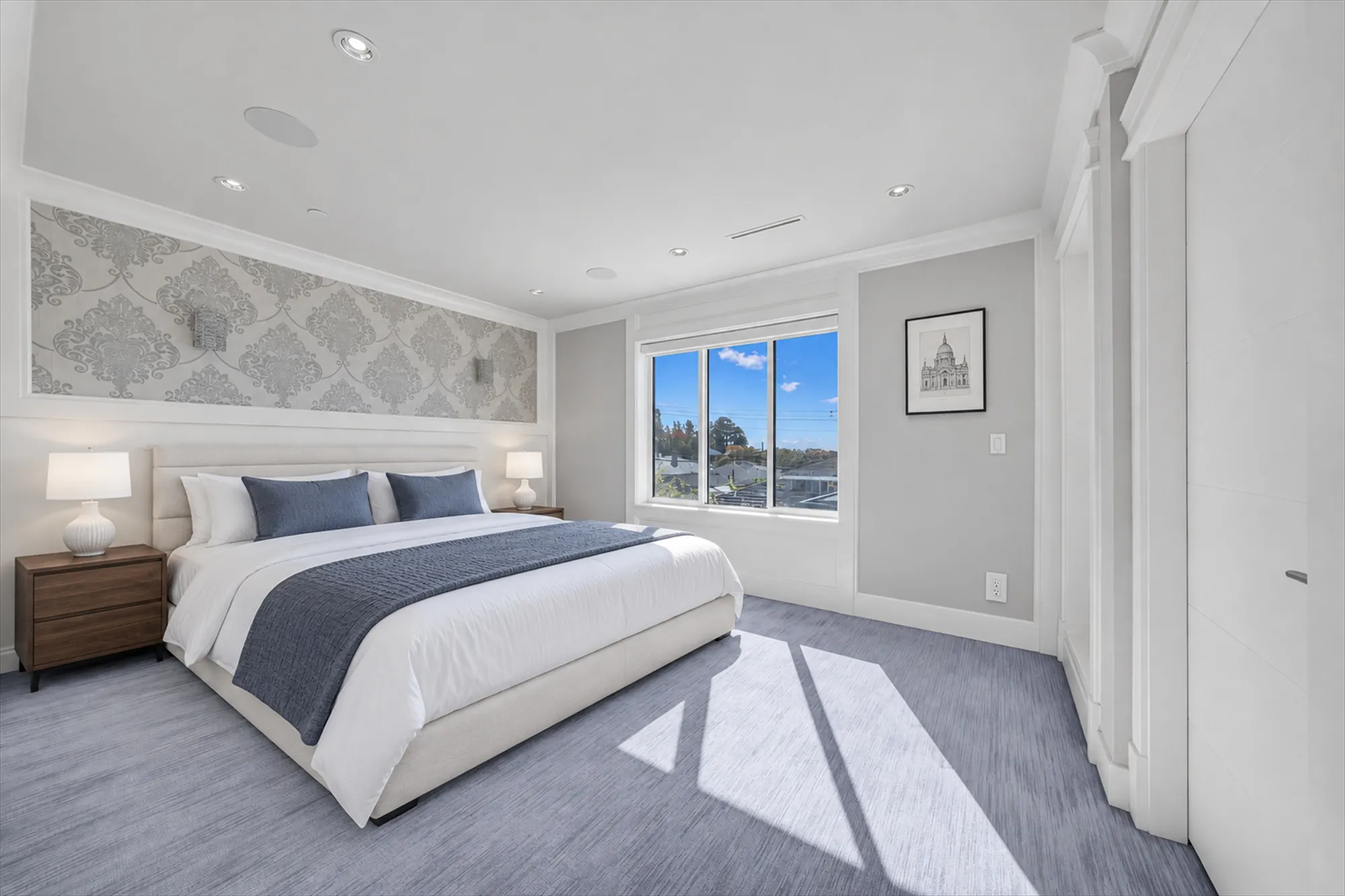 The same view virtually staged: a bed with a white headboard against the damask wall, night tables and lamps, a picture