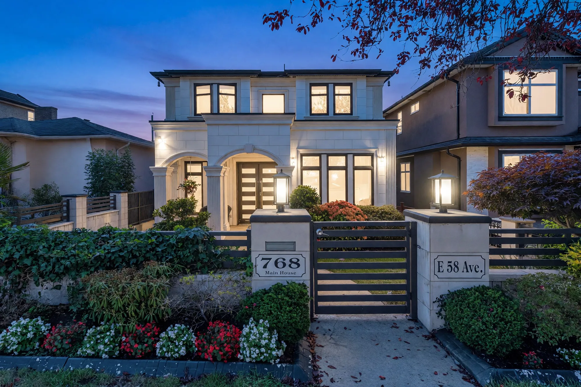 The same view from the street at dusk, the house lit